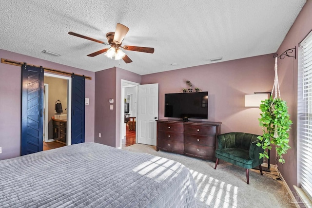 carpeted bedroom featuring ceiling fan, a barn door, and a textured ceiling