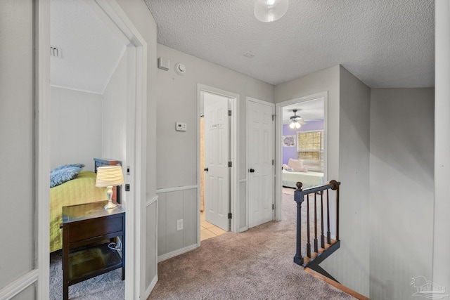 hallway featuring light colored carpet and a textured ceiling