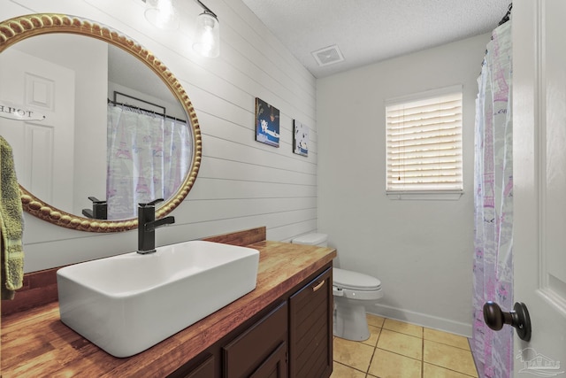 bathroom with tile patterned floors, toilet, a textured ceiling, and vanity