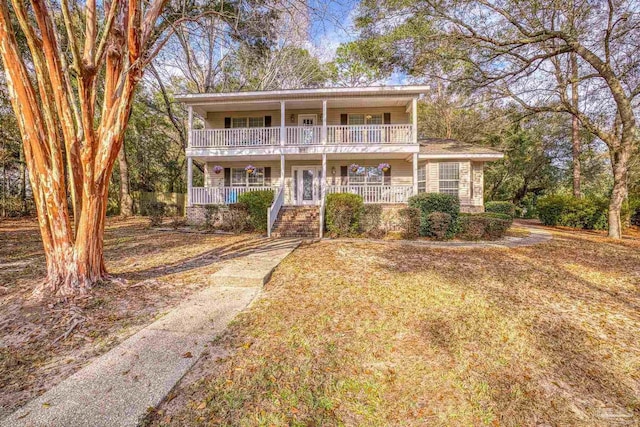 view of property with a balcony, covered porch, and a front lawn