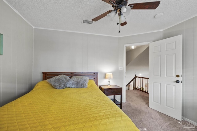 carpeted bedroom featuring ornamental molding, ceiling fan, and a textured ceiling