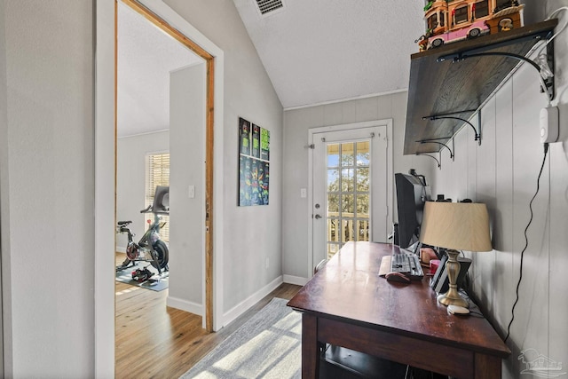 office area featuring lofted ceiling, light hardwood / wood-style flooring, a textured ceiling, and plenty of natural light