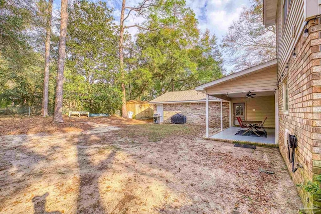 view of yard featuring a patio, ceiling fan, and a storage shed