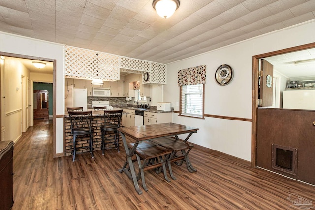 dining room with crown molding, sink, and dark hardwood / wood-style floors