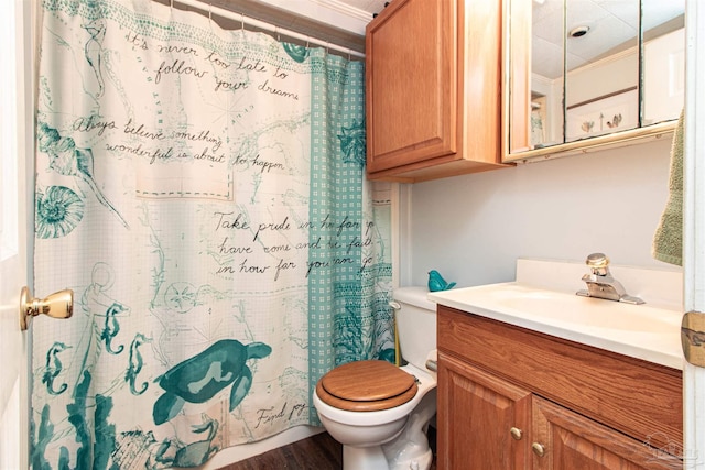 bathroom featuring vanity, hardwood / wood-style flooring, toilet, ornamental molding, and walk in shower