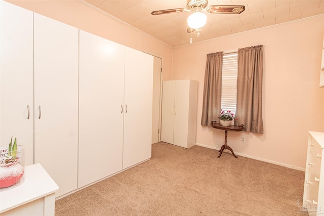 unfurnished bedroom featuring a closet, light colored carpet, ceiling fan, and ornamental molding