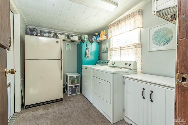 washroom featuring light carpet, washer and clothes dryer, and cabinets