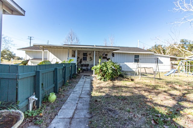 back of house with a playground