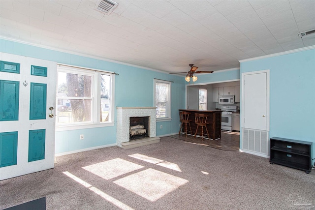 unfurnished living room featuring ceiling fan, carpet floors, and crown molding