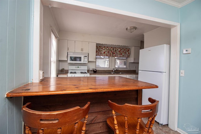 kitchen featuring white cabinetry, sink, crown molding, and white appliances