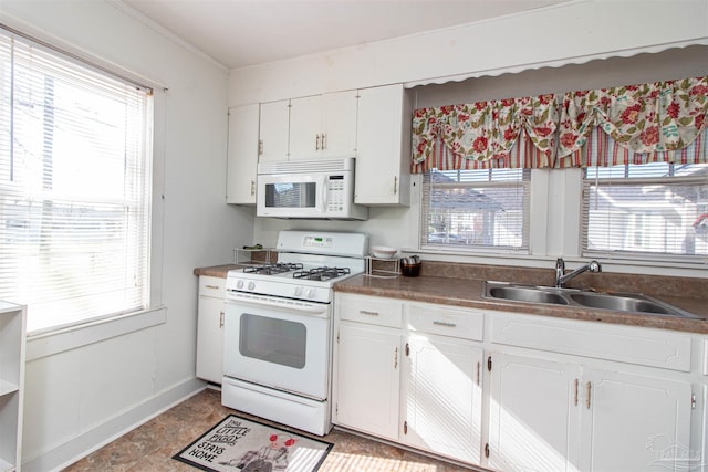 kitchen featuring white cabinetry, sink, a healthy amount of sunlight, and white appliances