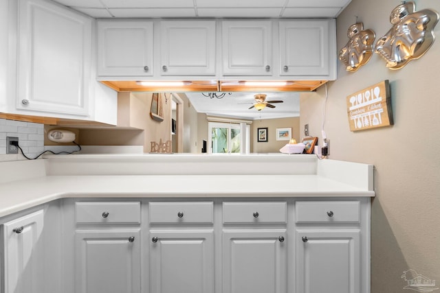 kitchen with ceiling fan, a drop ceiling, and white cabinets