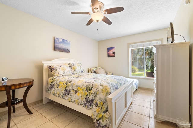 bedroom with ceiling fan, light tile patterned flooring, and a textured ceiling