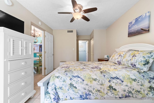 tiled bedroom featuring ceiling fan and a textured ceiling