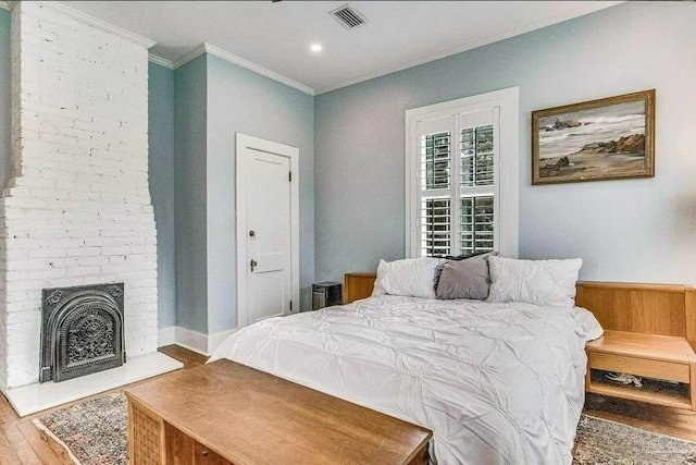 bedroom featuring crown molding, hardwood / wood-style floors, and a fireplace