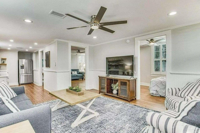 living room featuring crown molding, ceiling fan, and light wood-type flooring