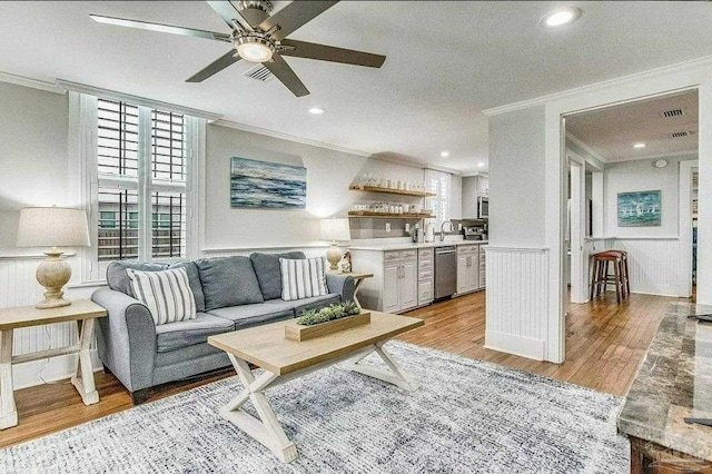 living room with crown molding, light hardwood / wood-style floors, and ceiling fan