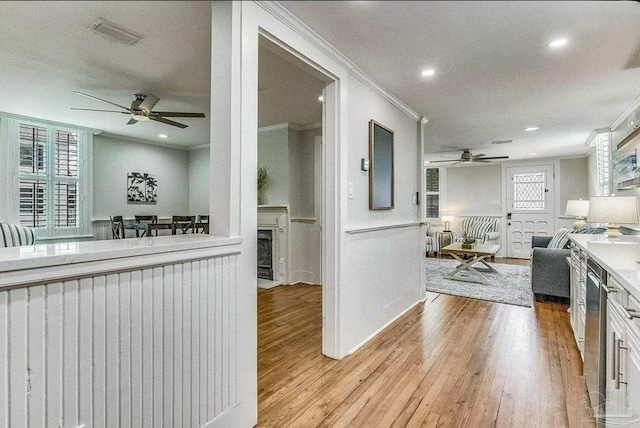 kitchen with ceiling fan, ornamental molding, white cabinets, and light wood-type flooring