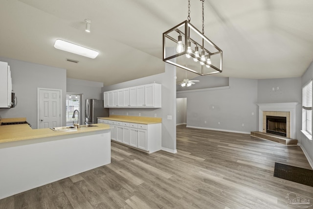 kitchen with lofted ceiling, a tile fireplace, a peninsula, a sink, and freestanding refrigerator