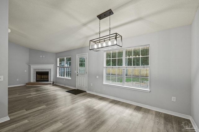 unfurnished living room featuring a textured ceiling, a tiled fireplace, baseboards, and wood finished floors