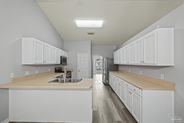 kitchen featuring light countertops, visible vents, appliances with stainless steel finishes, a sink, and a peninsula