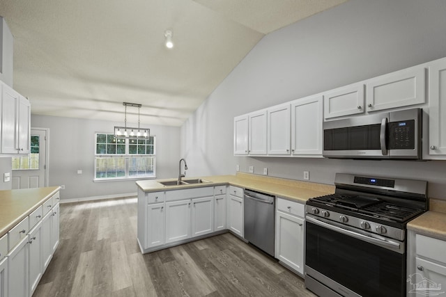 kitchen featuring white cabinetry, appliances with stainless steel finishes, vaulted ceiling, and a sink