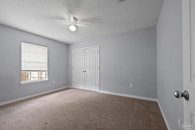 unfurnished bedroom with baseboards, ceiling fan, a textured ceiling, carpet floors, and a closet