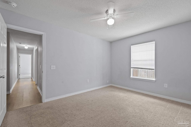 spare room featuring a textured ceiling, carpet floors, a ceiling fan, and baseboards