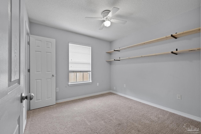 carpeted spare room with ceiling fan, baseboards, and a textured ceiling