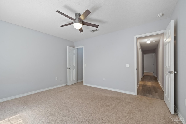 unfurnished bedroom featuring carpet floors, visible vents, ceiling fan, a textured ceiling, and baseboards