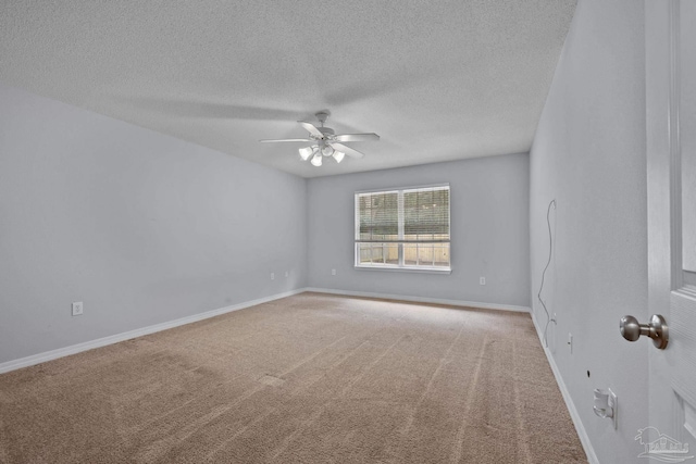 empty room with a textured ceiling, carpet floors, a ceiling fan, and baseboards