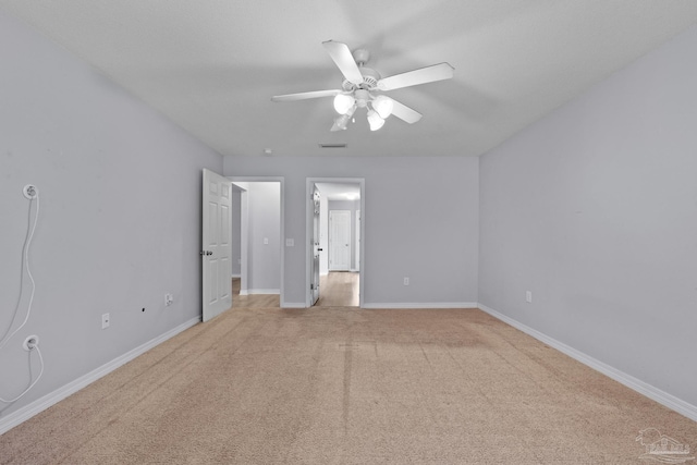 unfurnished bedroom featuring baseboards, ceiling fan, visible vents, and light colored carpet