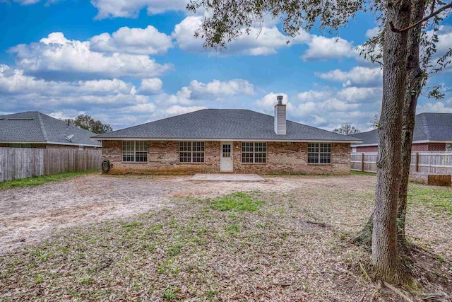 rear view of property with a patio, brick siding, a chimney, and a fenced backyard