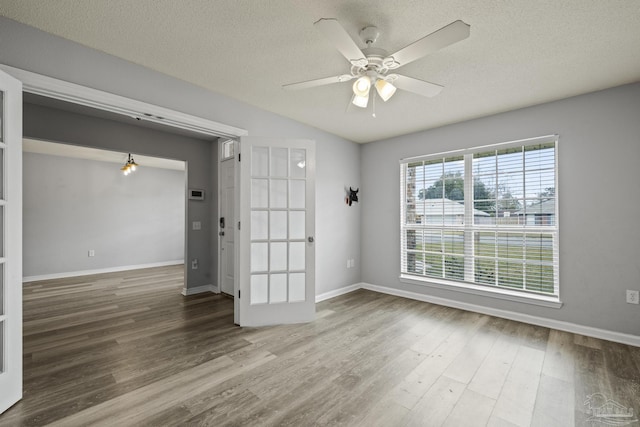 spare room with ceiling fan, a textured ceiling, and wood finished floors