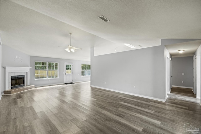 unfurnished living room featuring ceiling fan, lofted ceiling, a tile fireplace, wood finished floors, and visible vents