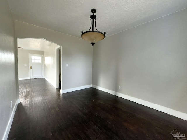 unfurnished dining area featuring dark wood-type flooring and a textured ceiling