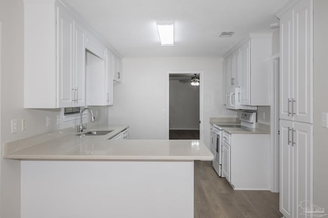 kitchen with a peninsula, a sink, white cabinetry, white appliances, and light countertops