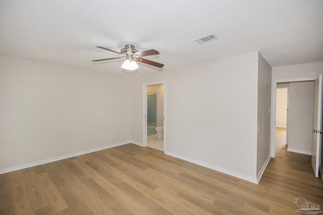 empty room featuring ceiling fan, light wood-style flooring, baseboards, and visible vents