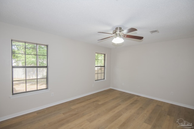 unfurnished room featuring a ceiling fan, a textured ceiling, baseboards, visible vents, and wood finished floors