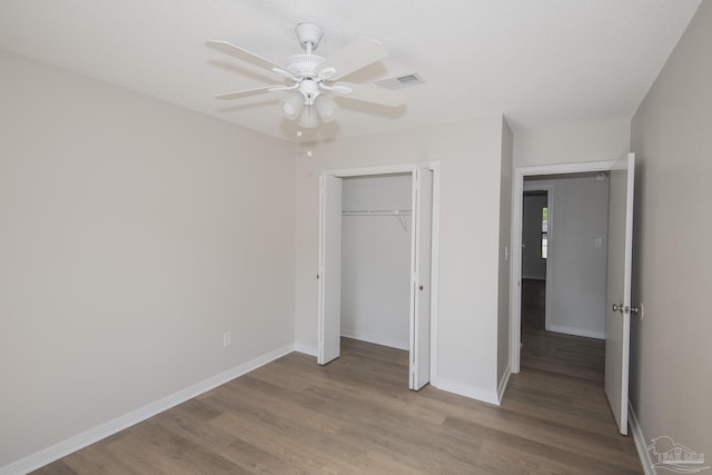 unfurnished bedroom featuring wood finished floors, a ceiling fan, a closet, visible vents, and baseboards