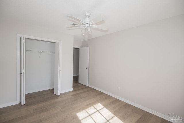 unfurnished bedroom featuring a closet, baseboards, a ceiling fan, and wood finished floors