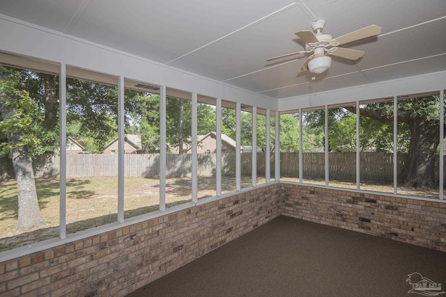 unfurnished sunroom with brick wall, ceiling fan, and a wealth of natural light