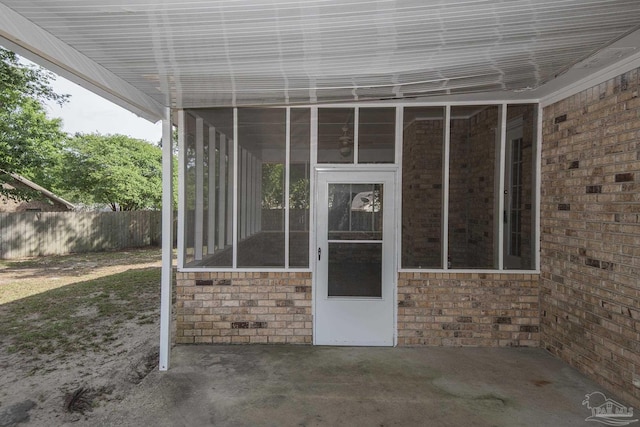 doorway to property with a patio area, fence, and brick siding