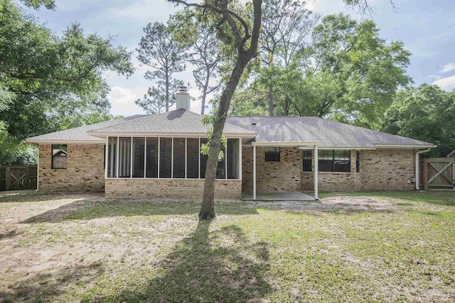 back of house with a yard, a chimney, a sunroom, and fence