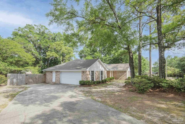 view of side of home with concrete driveway, brick siding, a garage, and fence