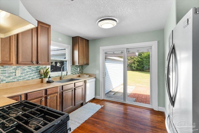 kitchen with sink, stainless steel fridge, range with gas stovetop, dishwasher, and dark hardwood / wood-style flooring