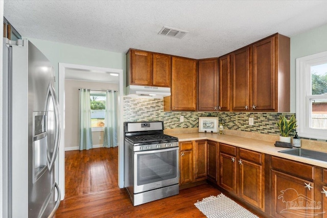 kitchen featuring tasteful backsplash, dark wood-type flooring, a textured ceiling, and appliances with stainless steel finishes