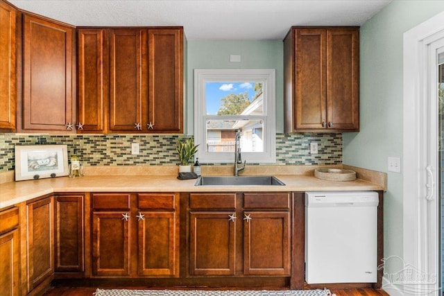 kitchen featuring white dishwasher, sink, and backsplash