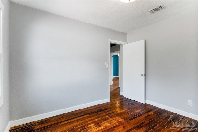 spare room with dark hardwood / wood-style floors and a textured ceiling