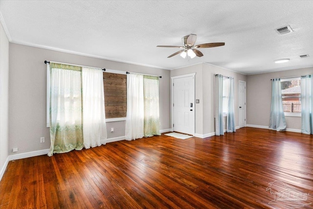 empty room with ceiling fan, plenty of natural light, dark hardwood / wood-style floors, and a textured ceiling